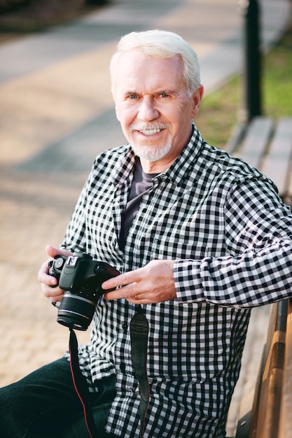 Foto beleef meer. heel volwassen man met behulp van camera en rusten op de bank