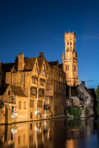 Belfry van Bruges bij de rivier tegen een heldere blauwe hemel in de schemering