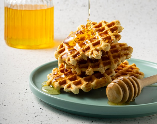 Belgian sugar waffles with flower honey on a blue plate