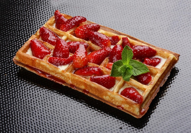 Belgian sweet waffle on a dark background Stuffed with strawberries and cream