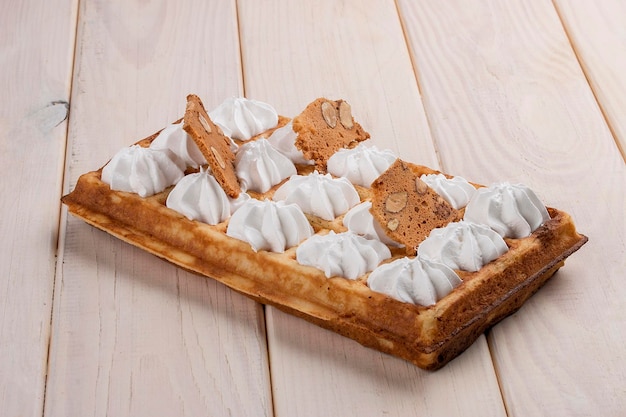 Belgian waffle meringue and almond chips On a light wooden background