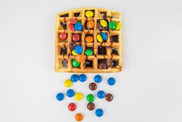 Belgian waffle with colored sweets and chocolate on a white background Delicious sweet sweet waffles View from above