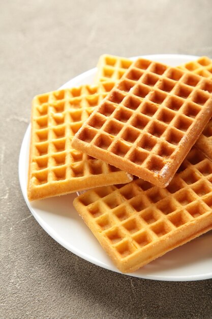 Belgian waffles. Belgian waffles on white plate on grey background. Freshly baked Belgian waffles.