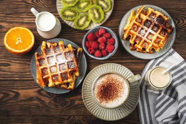 Belgian waffles, coffee, yogurt, fruits and berries on a wooden background, breakfast concept.