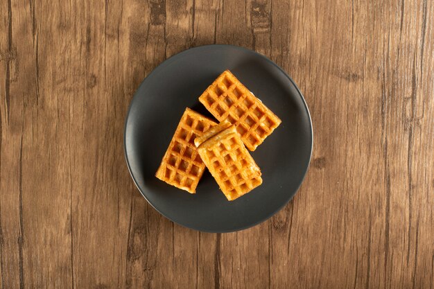 Belgian waffles on a saucer on a wood table. Top view