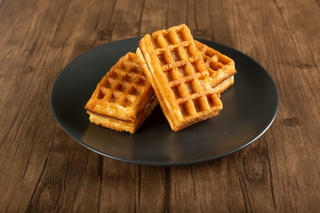 Belgian waffles on a saucer on a wood table.