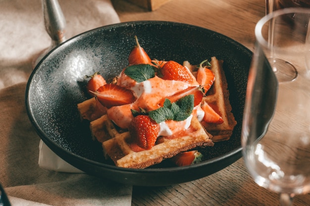 Belgian waffles with berries, ice cream and chocolate. Breakfast table setting. Morning lifestyle.