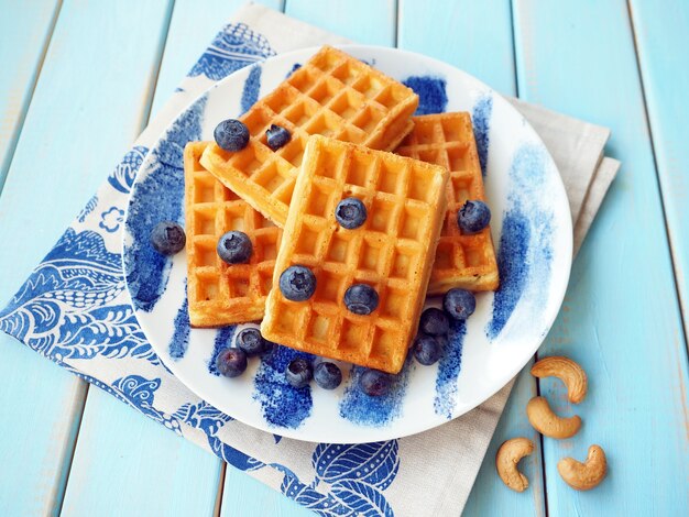 Photo belgian waffles with blueberries and nuts on blue table