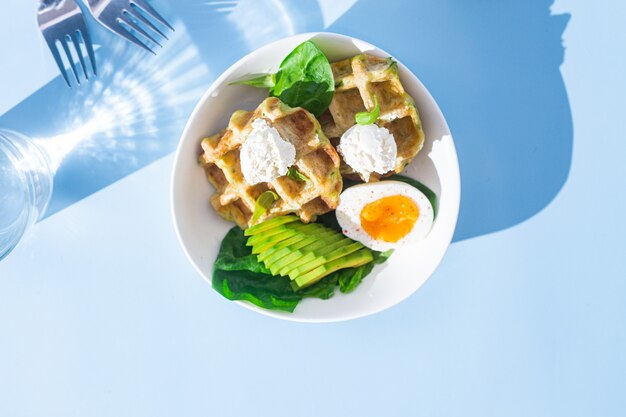 Belgian waffles with cream cheese egg and avocado in a white plate Healthy breakfast