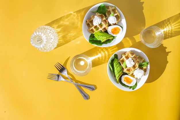 Belgian waffles with cream cheese egg and avocado in a white plate Healthy breakfast