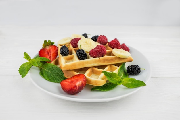 Belgian waffles with different berries on whiteSweet waffles in a white plate