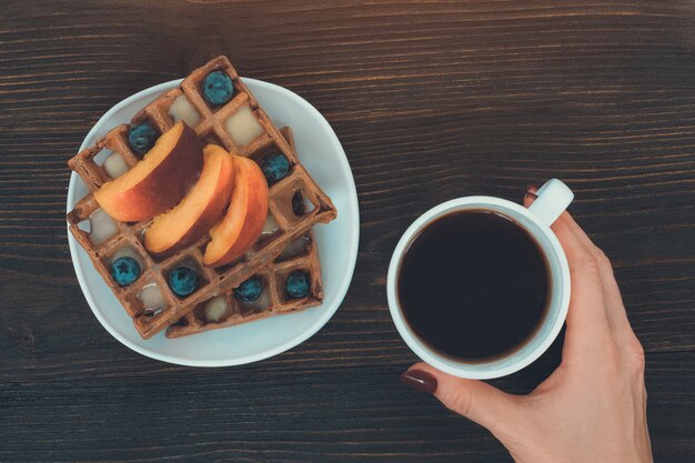 Belgian waffles with fruit and berries and cup of coffee