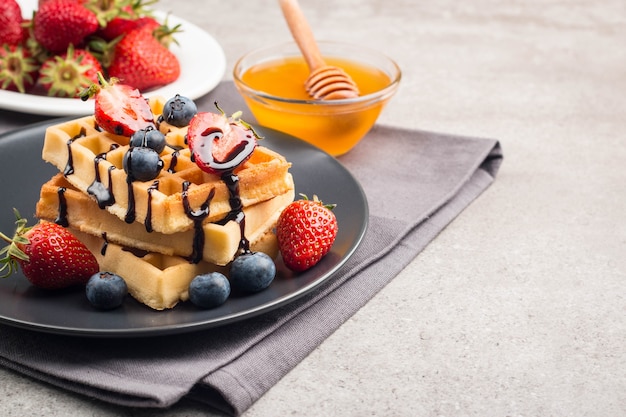 Belgian waffles with honey, chocolate, strawberry, blueberry, maple syrup and cream.