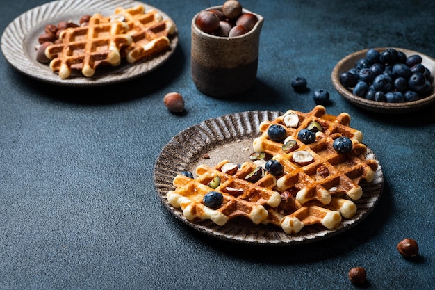 Belgian waffles with honey and fresh berries blueberry and hazelnut on dark background Delicious dessert Copy space Space for text Delicious breakfast