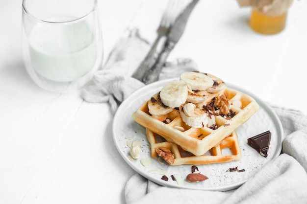 Belgian waffles with honey and nuts on a light background