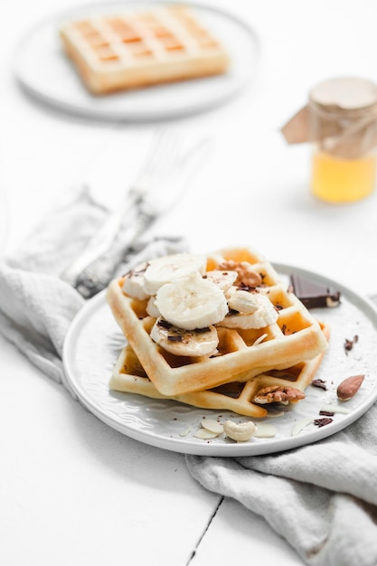 Belgian waffles with honey and nuts on a light background