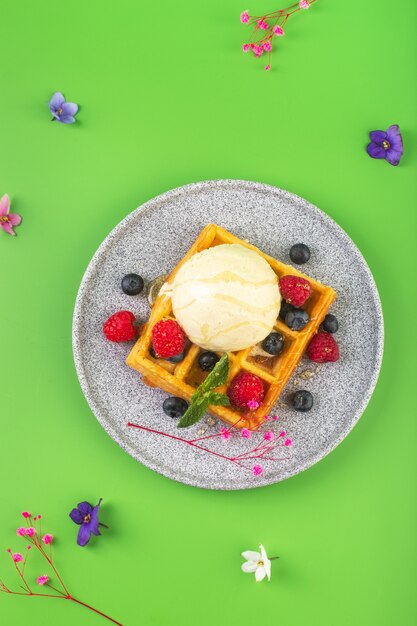 Belgian waffles with ice cream berries and flower on green high quality photo