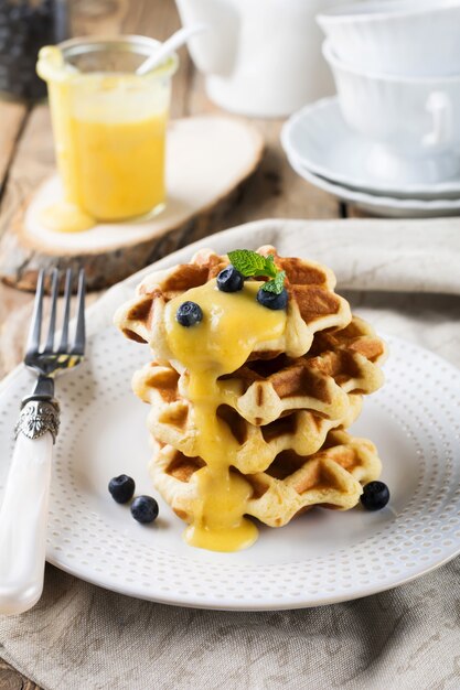 Belgian waffles with lemon Kurd and blueberries. Rustic style. Selective focus.