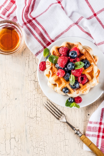 Belgian waffles with raspberries, blueberries and syrup, homemade healthy breakfast