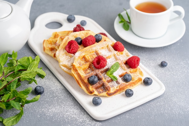 Belgian waffles with raspberries, blueberries, tea, side view. Healthy homemade breakfast