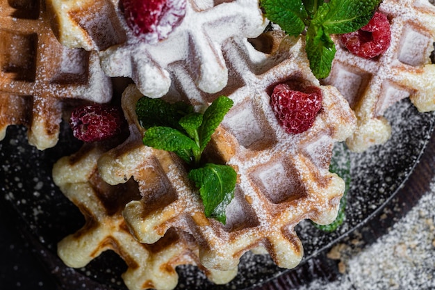belgian waffles with raspberries and mint on a dark plate