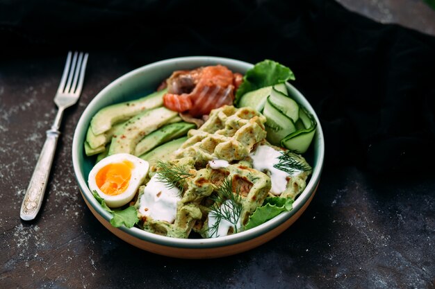 Belgian waffles with salmon avocado and egg in a plate