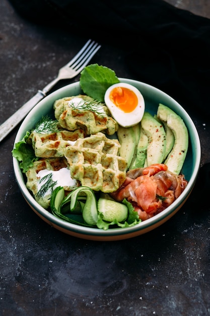 Belgian waffles with salmon avocado and egg in a plate