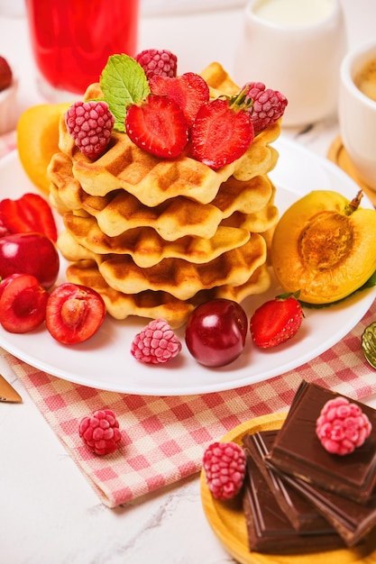 Belgian waffles with strawberries apricots cherries juice and a cup of black coffee