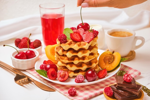 Belgian waffles with strawberries apricots cherries juice and a cup of black coffee