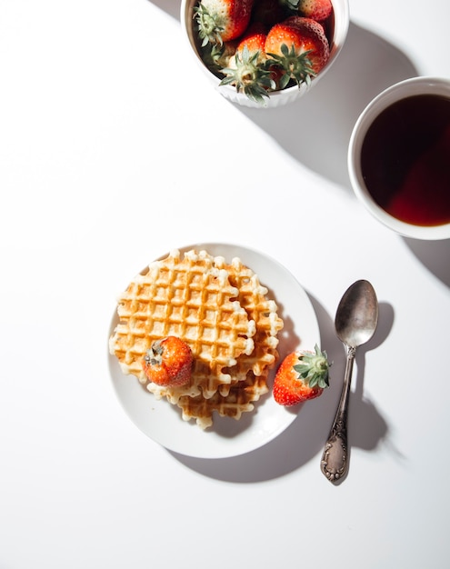 Waffle belgi con fragole su sfondo bianco