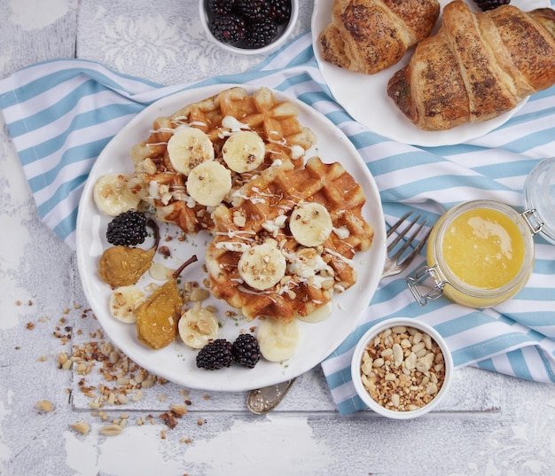 Belgian waffles with syrup, berries and honey, breakfast on a light background