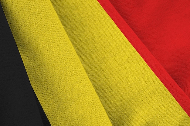 Belgische vlag met grote plooien die dicht omhoog zwaaien onder het studiolicht binnenshuis De officiële symbolen en kleuren in banner