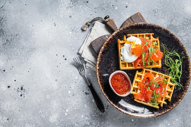 Belgische wafel met roomkaas, plakjes zalm, ei en rode kaviaar. Grijze achtergrond. Bovenaanzicht. Ruimte kopiëren.