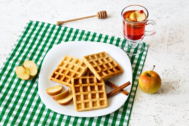 Belgische wafels, kaneelstokjes en appel op een plaat