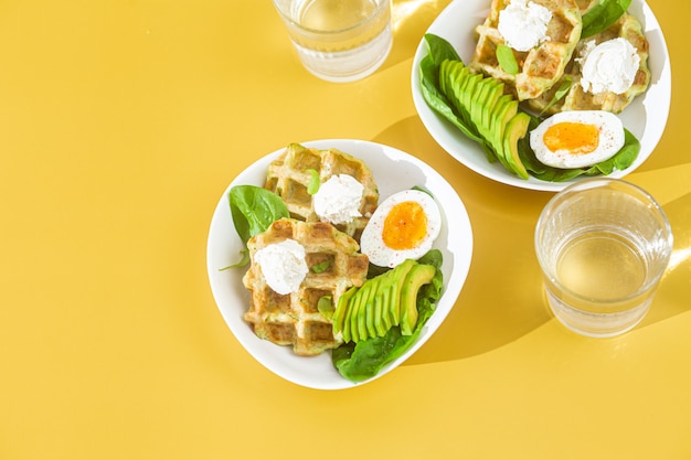 Belgische wafels met roomkaasei en avocado in een wit bord Gezond ontbijt