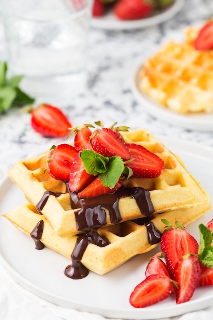 Belgium waffles with chocolate topping and strawberries. Breakfast food