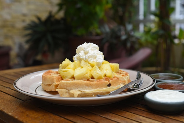 Belgium waffles with pineapple and ice ream on a wooden table