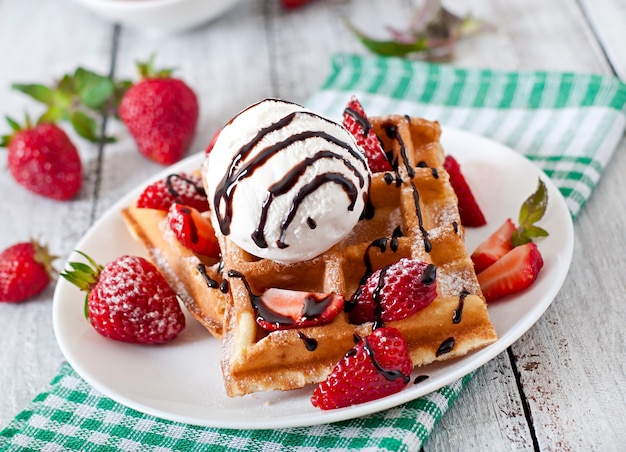 belgium waffles with strawberries and ice cream on white plate