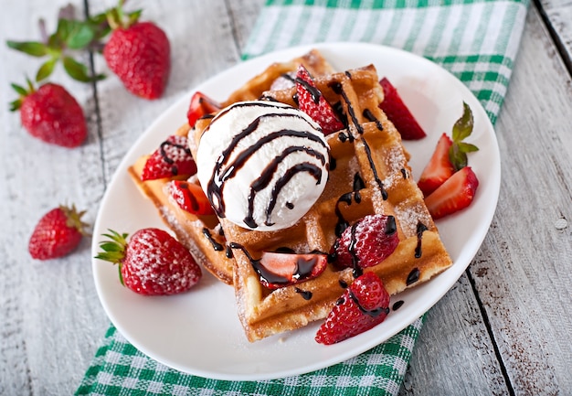 belgium waffles with strawberries and ice cream on white plate