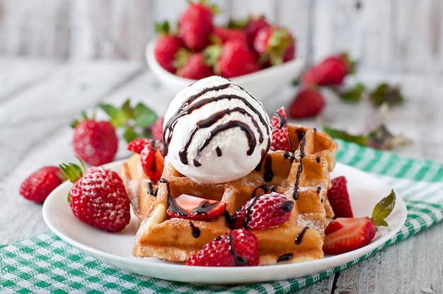 belgium waffles with strawberries and ice cream on white plate