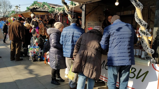 Belgrado Servië 24 januari 2020 Mensen in warme jassen kijken naar goederen in een straatwinkel Er zijn prachtig speelgoed en wijn in de etalage Souvenirbeurs Casual demiseason kleding
