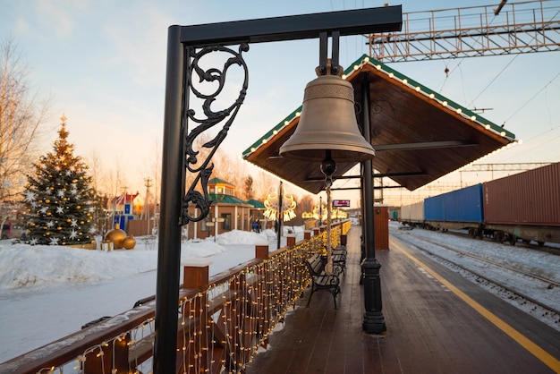 Photo a bell hangs from a pole in a train station.