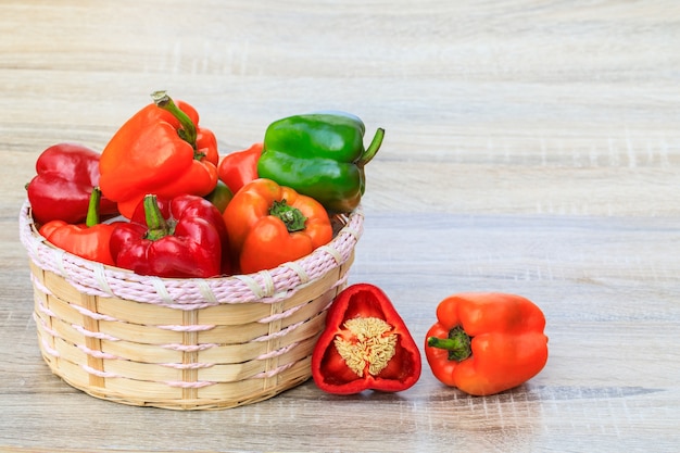 The bell pepper in the bamboo basket on wooden table.