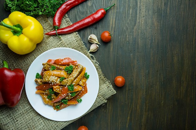 Bell pepper and meat salad. Asian food. Colorful hot salad. Dark background. Space for text.