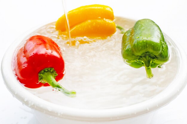 Bell pepper soaked in water. Washing fresh vegetables on white 