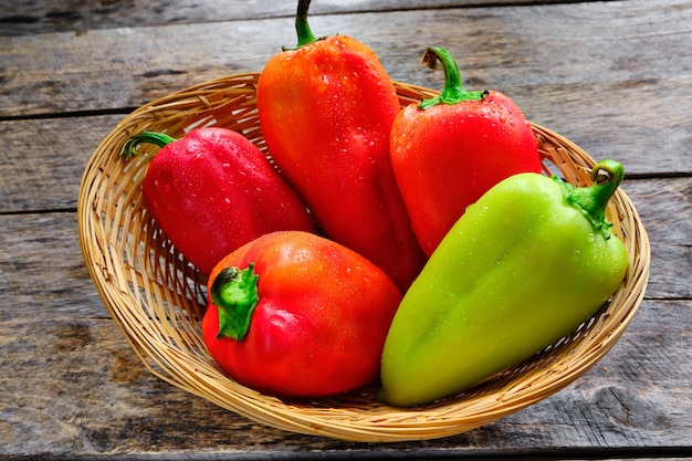 Bell peppers in a wicker basket on a rustic wooden table.