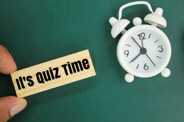 Photo bell and stick clock with the words its quiz time the concept of answering quizzes or quiz games