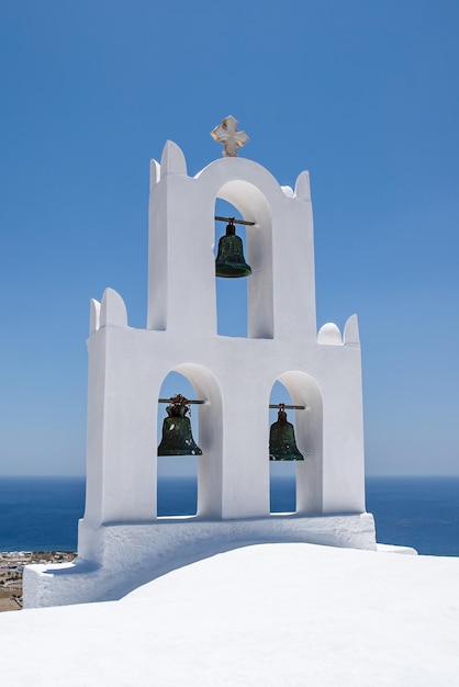 Bell tower of the traditional Greek tower on blue sea background