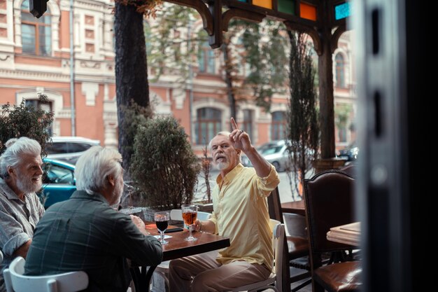 Bellen voor ober. Grijsharige, bebaarde man roept om ober terwijl hij buiten de pub zit