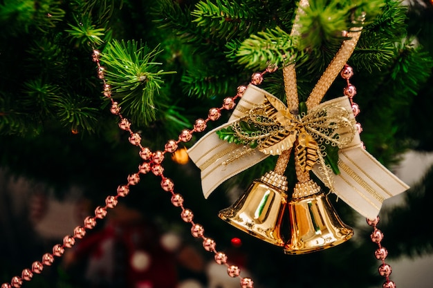 Photo bells hang on a branch of a christmas tree on a background of pink beads